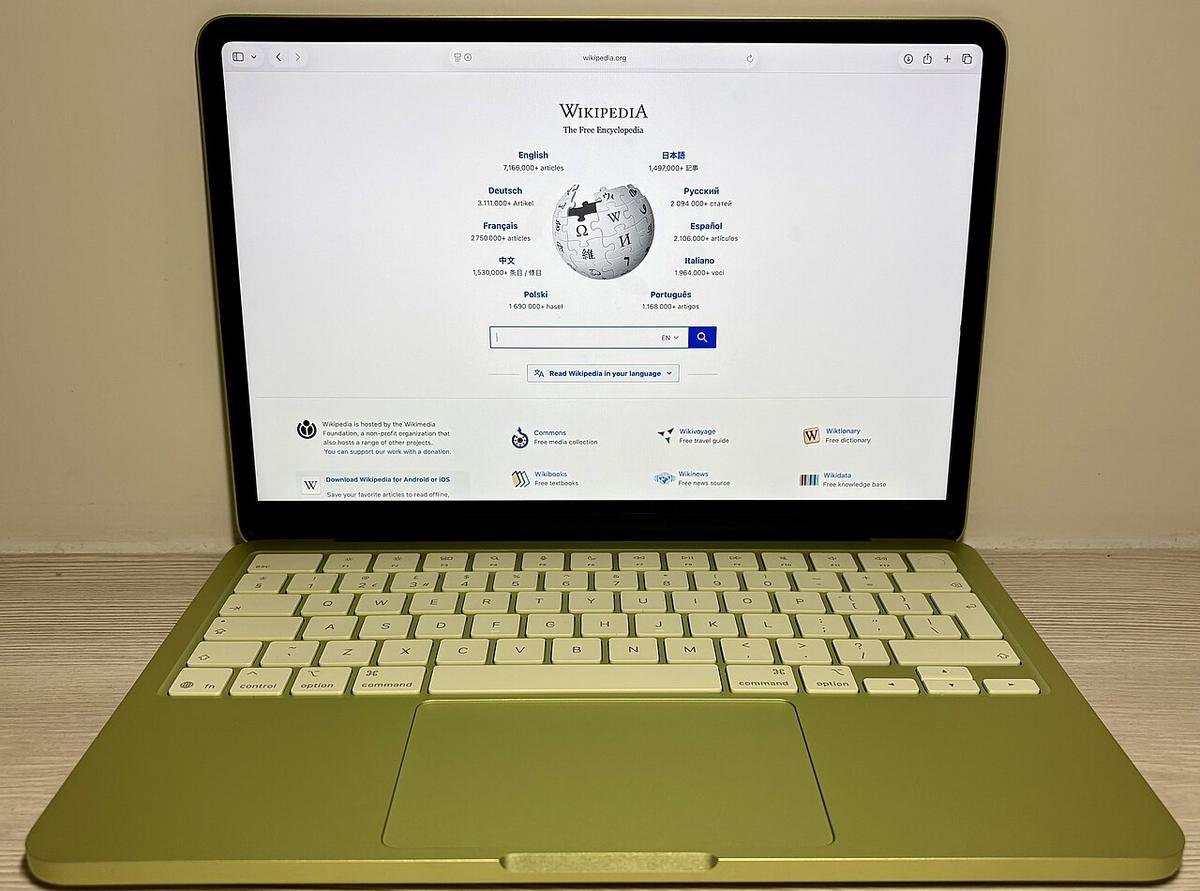 A yellow MacBook Neo open on a desk with Wikipedia on the screen